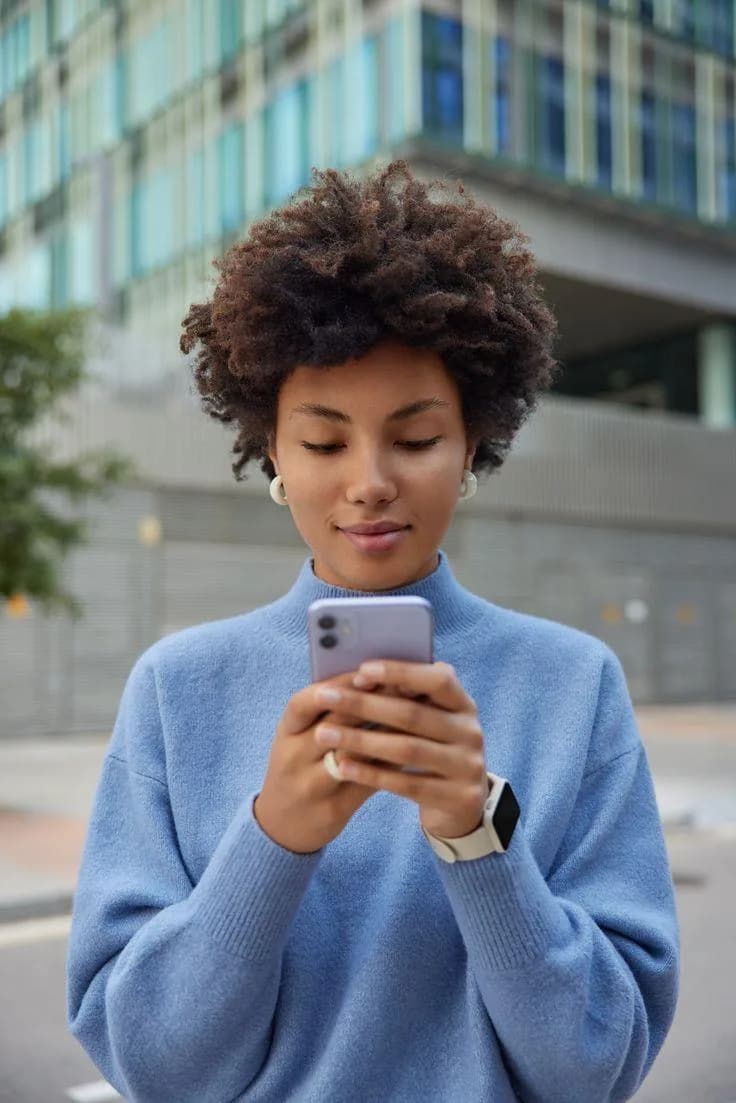 A woman texting on her phone outdoors in the city